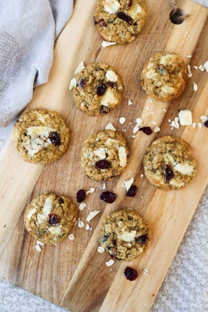Overhead view of oatmeal cranberry white chocolate cookies served on a wooden board.