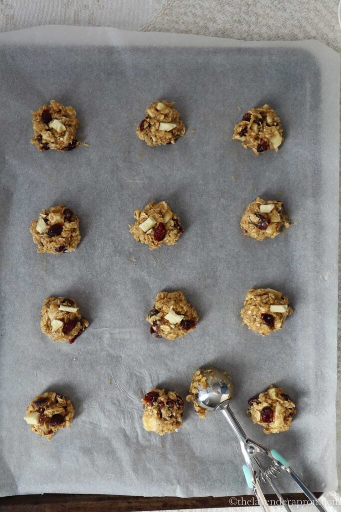 Balls of cookie dough placed on baking tray covered with parchment paper.